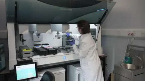 A researcher at the UK Dementia Institute in Edinburgh sets up a machine to test drugs on stem cell cultures