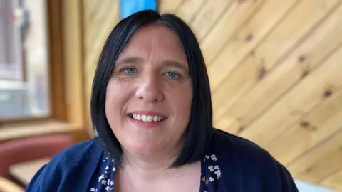 A head and shoulders photograph of Alice O'Hare, manager at Tanglewood Care Home. She is wearing a blue and white dress and a blue cardigan.