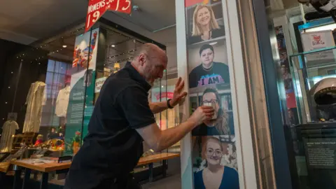 A man pasting down the portraits to a pillar inside the town hall.