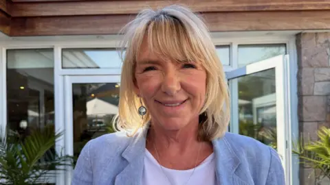 Natalie Parkin is pictured at her restaurant, she is wearing a blue blazer and white shirt. She has blonde hair.