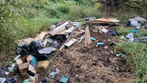 Somerset Council A mound of earth with blanks of wood and bags of rubbish on top