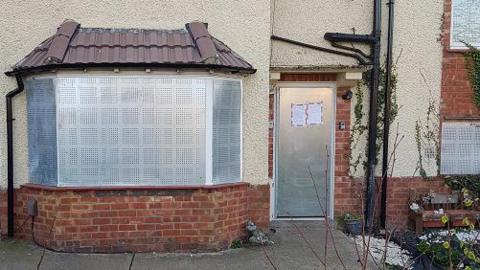 A house on Irthlingborough Road, Finedon, Northants, boarded up by police