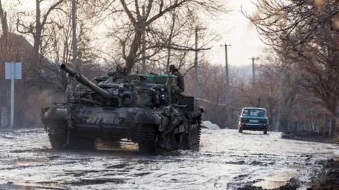 Getty Images An armoured vehicle pulls a Ukrainian T-72 tank in the village of Horlivka, Donetsk region, in February 2015