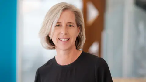 Hudgell Solicitors A woman with blonde hair in a bob is smiling into the camera for a professional head and shoulders shot. She is wearing a black top and the background is blurred.