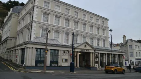 N Chadwick / Geograph the Empire Hotel yang merupakan bangunan besar, terpisah, krim di jalanan. Ada mobil di depan hotel, itu adalah warna emas.