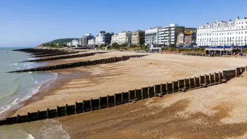 The shingled Eastbourne seafront with a line of buildings behind the promenade.