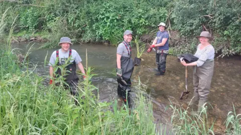 Sarah Perry Four volunteers stand in a chalk stream in Hertfordshire