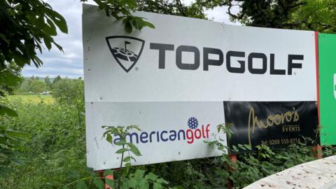 A sign for Topgolf placed at its entrance driveway