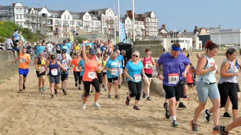 East Riding of Yorkshire Council Competitors wearing racing gear run along the beach at Bridlington