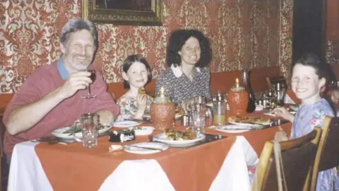 Press Association/Kent Police The Russell family, pictured at an Italian restaurant in early 1996. Youngest child Megan is sat between her parents, Shaun and Lin Russell, with Josie sat across the table. There are plates of food and drinks on the table and all four are smiling at the camera. 