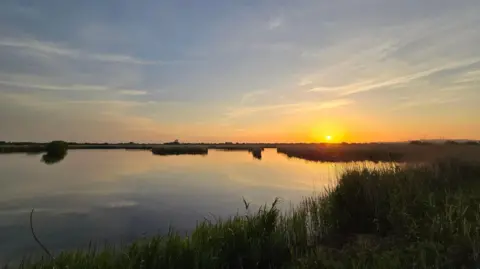 Gazzer The sun sets on a body of water.