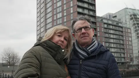 Suzy and Colin stand outside their blocks of flats in Salford 