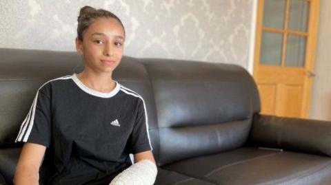 Ana Paun, 11, sitting on a sofa with a cast on her arm after the attack