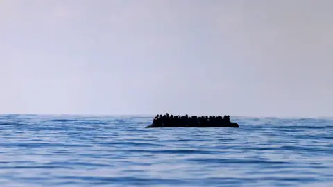 Getty Images A small boat crowded with people floats in the sea