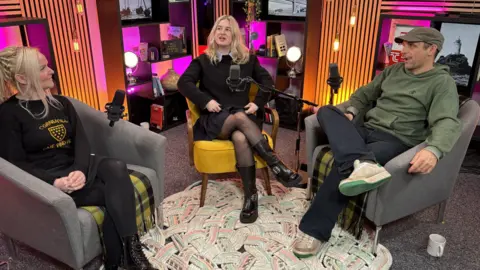 Three people in conversation in a podcast studio
