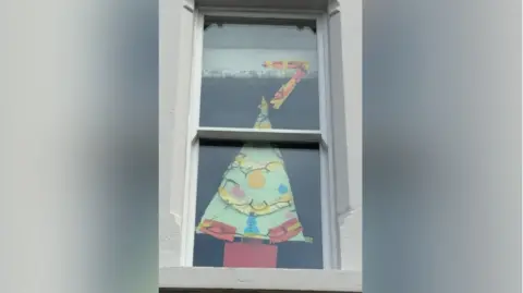 Emma Lawrence-Jones A window as part of the Advent display, decorated with a Christmas tree and the number 7.