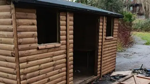 Friends of Moor Park The exterior of the wooden shed. Its windows and door are missing.