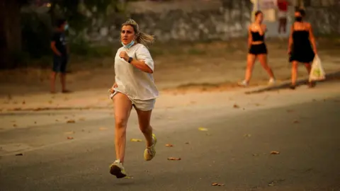 A person runs as the fire spreads in the mountains of Navaluenga, Avila, Spain