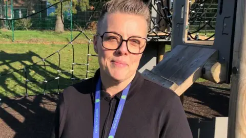 Vikki Irwin/BBC A female headteacher standing in front of a climbing frame in the school playground of Castle East Academy School.