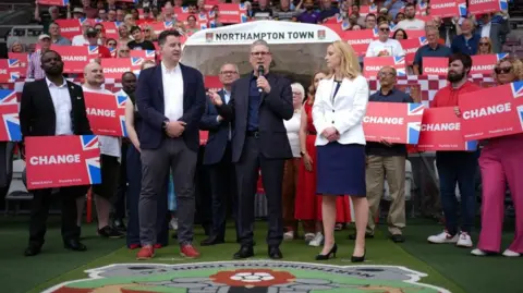 PA Media Keir Starmer with microphone surrounded by supporters with red placards