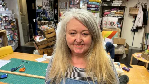 BBC/RICHARD EDWARDS This is a picture of Castleford artist Caroline Clarke-Green, who wants the new Wakefield Council to continue regeneration work being done in her home town.
She is smiling at the camera, has long, fair hair, and is wearing a denim dress and a top with thin black-and-white hoops.