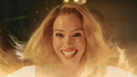 BBC Billie Piper pictured in the final episode of Doctor Who's most recent series, smiling at the camera amidst an orange glow