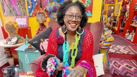 A woman with glasses wearing a colourful crocheted outfit