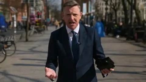 Mark Easton standing on a street wearing a suit and tie