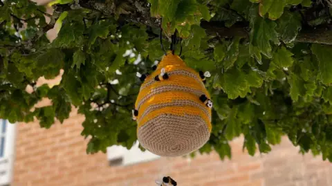 Imagine Formby A knitted beehive hangs from a tree