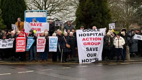 Crowds of people outside the hospital in Goole. Some are holding placards which read "save our hospital", "Goole Hospital action group", and "Hands off Goole Hospital".