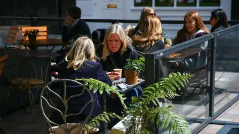 People sit at outdoor dining tables set up outside a restaurant at Covent Garden in London, U.K