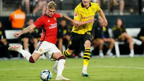 Reuters Brandon Williams in the a red shirt, white shorts and socks against Borussia Dortmund in yellow shirt, black shorts and yellow socks with black stripes at the Allegiant Stadium, Las Vegas, Naveda 30 July 2023.