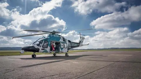 Air Ambulance Charity Kent Surrey Sussex The image shows a helicopter in a runway.