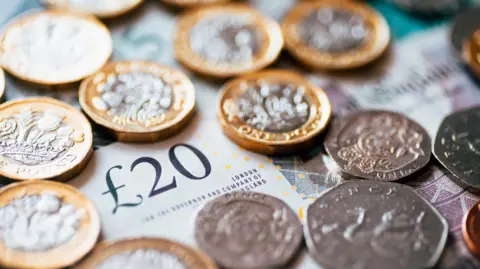 British pound coins scattered across a 20 pound note.