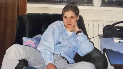 An old photograph of Izabela sat down wearing a blue denim jacket
