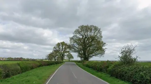 Google Streetview image of Sheepy Lane, a rural road with thick hedges and fields either side
