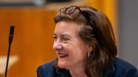 Senedd Cymru Eluned Morgan smiling in the Senedd debating chamber