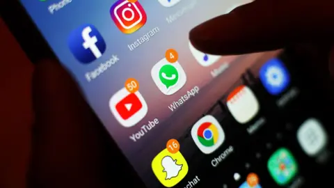 This is a stock photo of a close up of a mobile phone screen showing various apps with notifications.