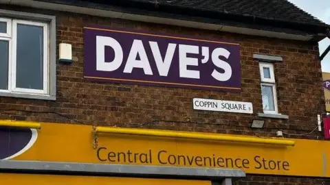 Stevie Moore A purple sign on a brick building, with "Dave's" written on it in capital bold white letters. Below it is the yellow storefront sign reading "central convenience store"