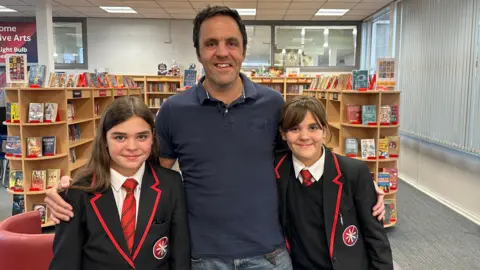 BBC Maisie and Grace Tooley, being embraced by their dad 