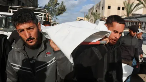 Mourners carry the body of a Palestinian who was reportedly killed in an Israeli air strike, at Nasser hospital, in Khan Younis, southern Gaza (4 February 2026)