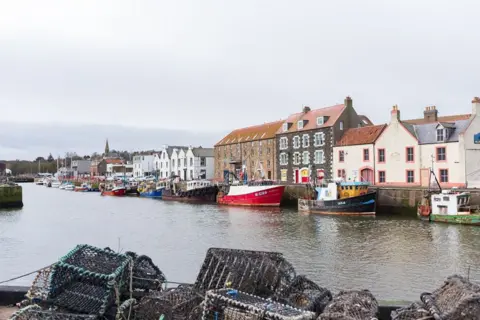 Getty Images Another view of Eyemouth harbour with some fishing creels in the foreground and boats and houses in the background