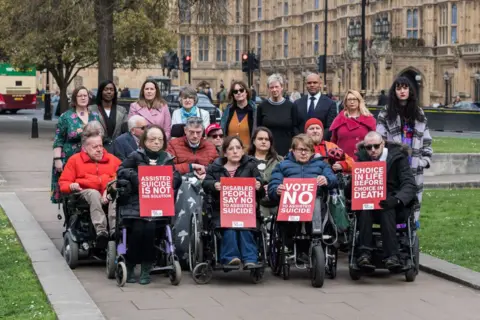Getty Images A small group of people including some using wheelchairs protest outside Westminster against assisted dying