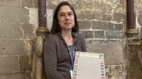 Jo Burn / BBC Cressida Williams holding a copy of the Canterbury charter