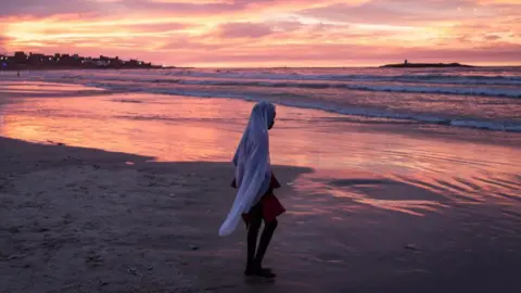 John Wessels/AFP Foto van een jong meisje dat op het strand loopt in Dakar, Senegal tijdens de viering van de geboorte van de profeet Mohammed - zondag 15 september 2024. 