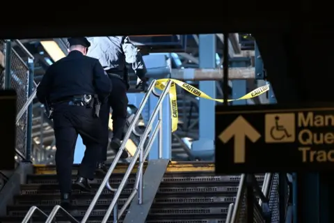 Getty Images A shot of two police officers from behind walking up a staircase at a subway station