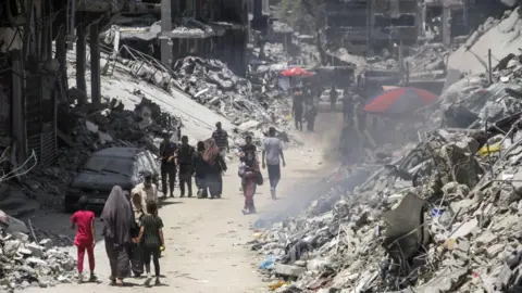 Getty Images People walk through the destroyed streets of Khan Yunis