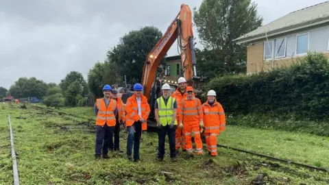 North Somerset Council Several people in high-vis overalls standing in front of a digger