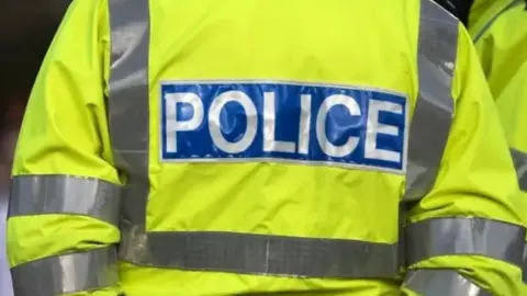The back of a police high-vis jacket. It says "Police" on it in white lettering in a blue rectangle.