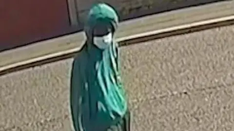 Merseyside Police CCTV image of Axel Rudakubana wearing a green hoody with the hood up and a surgical face mask.